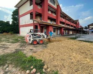 Proses meratakan tanah top soil untuk tanam rumput padang sekolah menggunakan mesin
