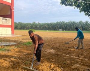 Proses meratakan tanah top soil untuk tanam rumput padang sekolah secara manual